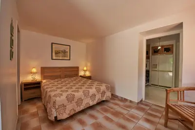 a bedroom with a bed and a table and a chair at Maison L'Olivier avec piscine in Cuttoli-Corticchiato
