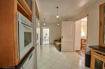 a kitchen with a stove top oven and a living room at Maison L'Olivier avec piscine in Cuttoli-Corticchiato