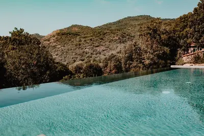 a swimming pool with a mountain in the background at L'Aiglon in Serriera