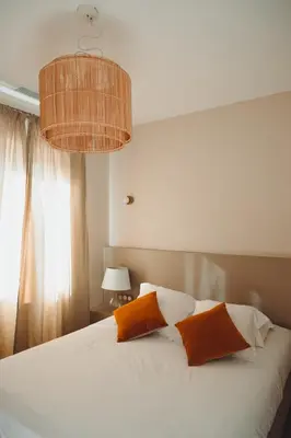 a bedroom with a white bed with two orange pillows at L'Aiglon in Serriera