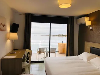 a hotel room with a bed and a desk and a window at Hôtel du Golfe in Sartène