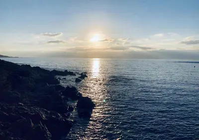 a sunset over the ocean with a rocky shore at Hôtel du Golfe in Sartène