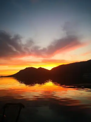 a sunset on a lake with mountains in the background at seuls à bord dans le golfe hebergement atypique in Porto-Vecchio