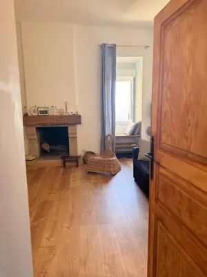 a living room with a fireplace and a wooden door at Location atypique village olmeto in Olmeto