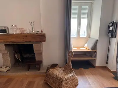 a living room with a fireplace and a chair at Location atypique village olmeto in Olmeto