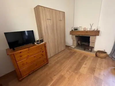 a living room with a television on a dresser with a fireplace at Location atypique village olmeto in Olmeto