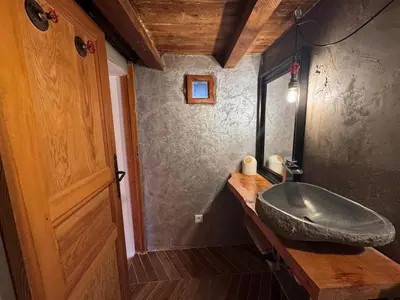a bathroom with a large stone sink on a wooden counter at Location atypique village olmeto in Olmeto