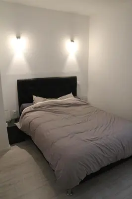 a bed in a bedroom with two lights on the wall at Appartement Sampiero in Corte