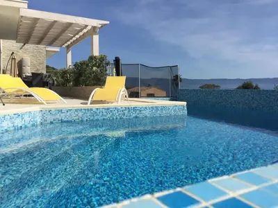a swimming pool with two yellow chairs next to a house at Vizzavona Piscine in Ajaccio