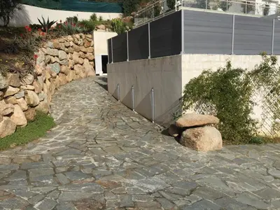 a stone path in front of a building with two rocks at Vizzavona Piscine in Ajaccio