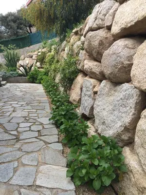 a stone path next to a rock wall at VIzzavona piscine et jacuzzi in Ajaccio