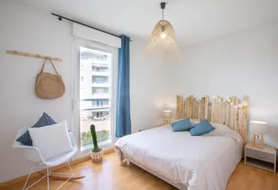 a bedroom with a bed and a chair and a window at Evasion Marine - T2 Vue mer - Terrasse - Plage à pied in Ajaccio