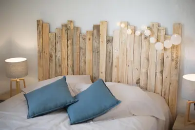 a bed with two blue pillows in front of a wooden wall at Evasion Marine - T2 Vue mer - Terrasse - Plage à pied in Ajaccio