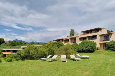 a group of lounge chairs sitting in a field at Hotel Bartaccia in Propriano