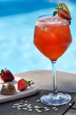 a drink in a glass with a strawberry on a table at Hotel Bartaccia in Propriano