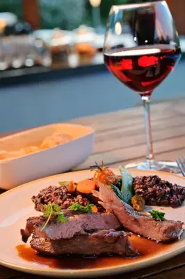 a plate of food with meat and a glass of wine at Hotel Bartaccia in Propriano