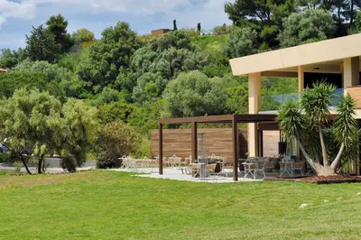 a building with tables and chairs in a park at Hotel Bartaccia in Propriano