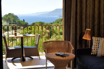 a room with a balcony with a table and chairs at Hotel Bartaccia in Propriano