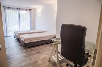 a bedroom with two beds and a desk and a chair at Appartement Gialla in Porto-Vecchio