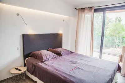 a bedroom with a large bed with a large window at Appartement Gialla in Porto-Vecchio