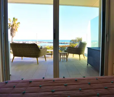 a bedroom with a view of the ocean from a balcony at TADO in Kamiesch