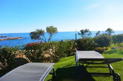 a picnic table and a bench next to the ocean at TADO in Kamiesch