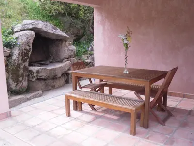 a wooden table and a bench with a vase on it at Casa Myrta 3 étoiles in Porto-Vecchio