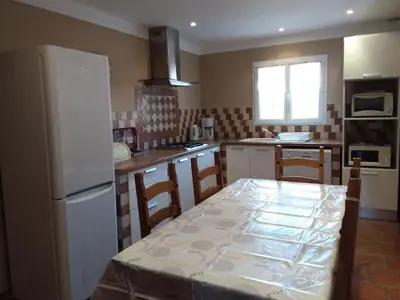 a kitchen with a table and a white refrigerator at Casa Myrta 3 étoiles in Porto-Vecchio