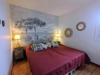 a bedroom with a red bed with a painting on the wall at Appartements L'Acacia - plage d'Argent à 300m in Coti-Chiavari