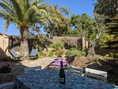 a bottle of wine sitting on a table in a garden at Appartements L'Acacia - plage d'Argent à 300m in Coti-Chiavari