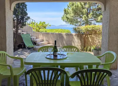 a green table and chairs with a bottle of wine at Appartements L'Acacia - plage d'Argent à 300m in Coti-Chiavari