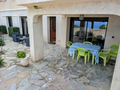a patio with a table and chairs on a stone patio at Appartements L'Acacia - plage d'Argent à 300m in Coti-Chiavari