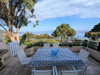 a table and chairs on a patio with a view of the water at Appartements L'Acacia - plage d'Argent à 300m in Coti-Chiavari