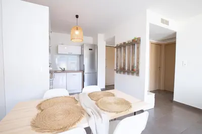 a white kitchen with a table and white chairs at T2 au coeur de Porticcio - Vue mer Imprenable ! in Grosseto-Prugna