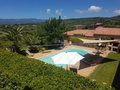 a swimming pool with umbrellas and a house at sci marie dominique in Olmeto
