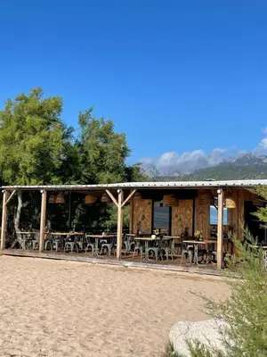 a building with tables and chairs on the beach at Palauma Plage in Sari Solenzara