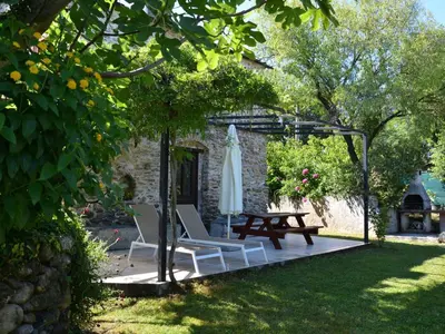 a patio with two chairs and a table and a umbrella at Holiday Home Moriani-Plage with Pool in San-Nicolao