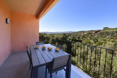 a wooden table and chairs on a balcony with a view at SARL valinco locations in Olmeto