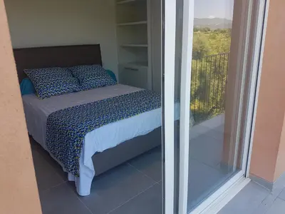 a bedroom with a bed and a view of a balcony at SARL valinco locations in Olmeto