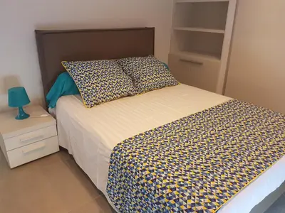 a bedroom with a bed with a checkered bedspread and a night stand at SARL valinco locations in Olmeto