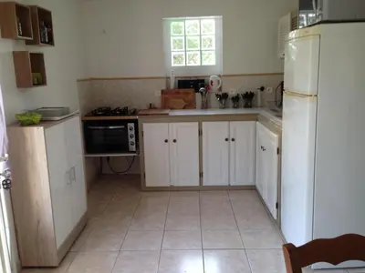 a kitchen with white cabinets and a white refrigerator at Riverside Home in Folelli in Penta-di-Casinca