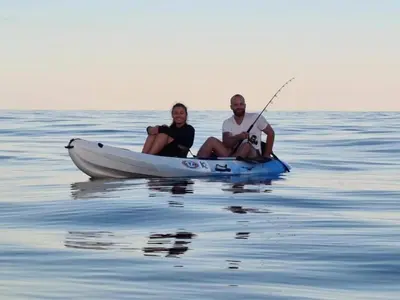 a man and woman sitting in a boat on the water at Riverside Home in Folelli in Penta-di-Casinca