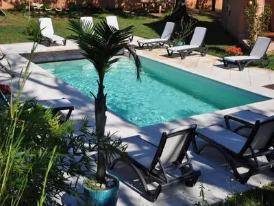 a palm tree sitting next to a swimming pool with chairs at Delightful Villa at Moriani-Plage with Garden in San-Nicolao