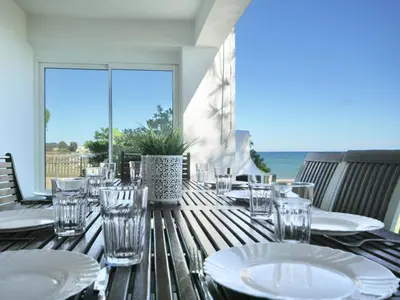 a table with plates and glasses on a table with the ocean at Villa in Moriani-Plage by the Sea in San-Nicolao