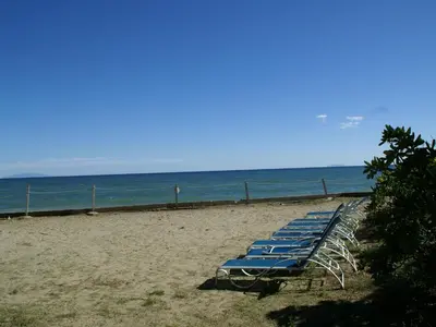 a row of blue lounge chairs on a beach at Villa in Moriani-Plage by the Sea in San-Nicolao
