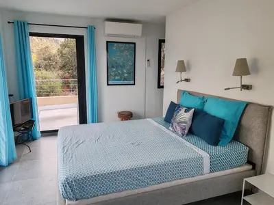 a bedroom with a bed with blue pillows and a window at Villa neuve architecte vue mer in Belvédère