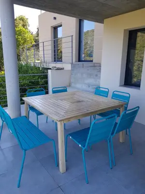 a wooden table and blue chairs on a patio at Villa neuve architecte vue mer in Belvédère