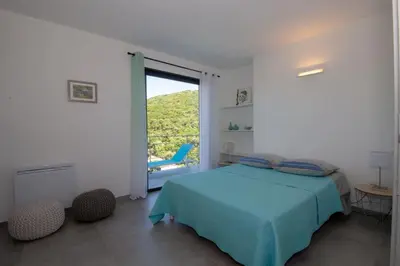 a bedroom with a blue bed and a large window at Villa neuve architecte vue mer in Belvédère