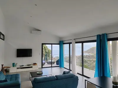 a living room with blue furniture and large windows at Villa neuve architecte vue mer in Belvédère