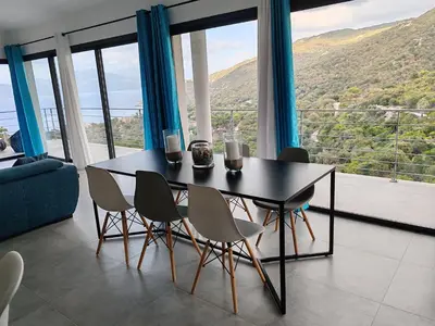 a dining room with a table and chairs with a view at Villa neuve architecte vue mer in Belvédère